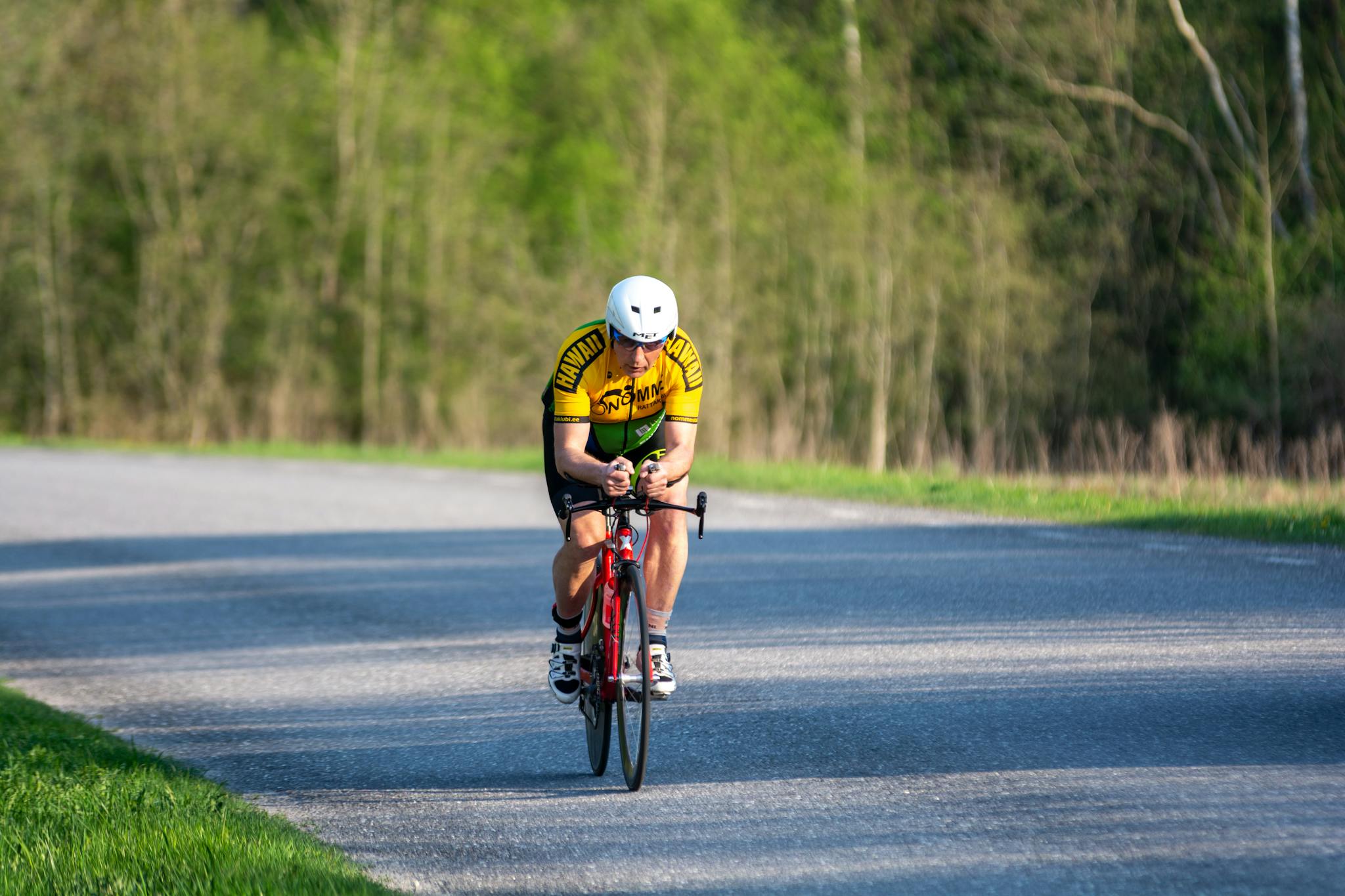 A solo cyclist racing on a scenic rural road in vibrant athletic gear.