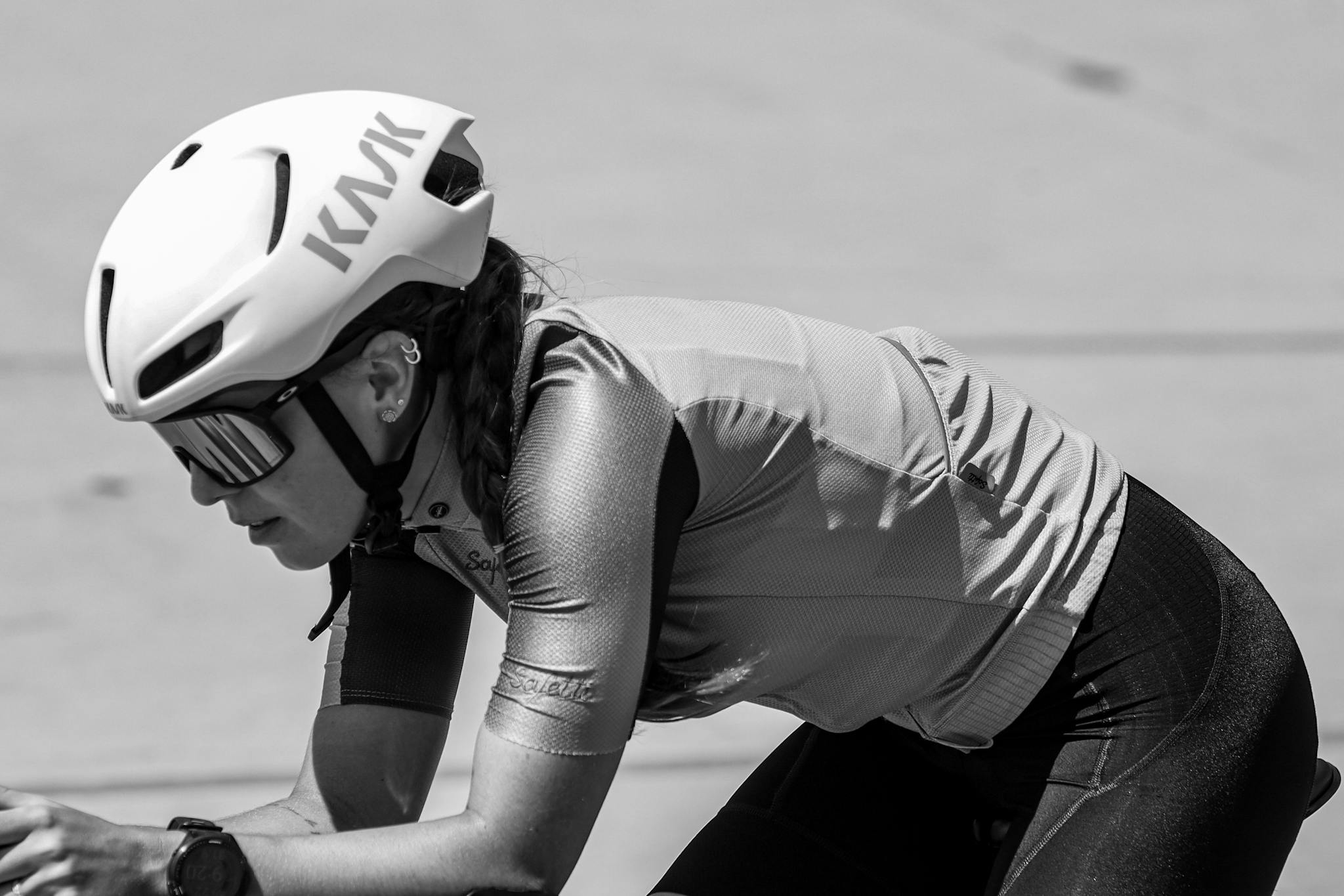 Close-up shot of a female cyclist in motion. Black and white tones.