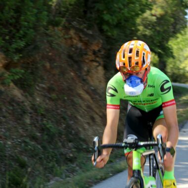 High-performance cyclist using VO2 mask on a winding road, showcasing speed and endurance training.