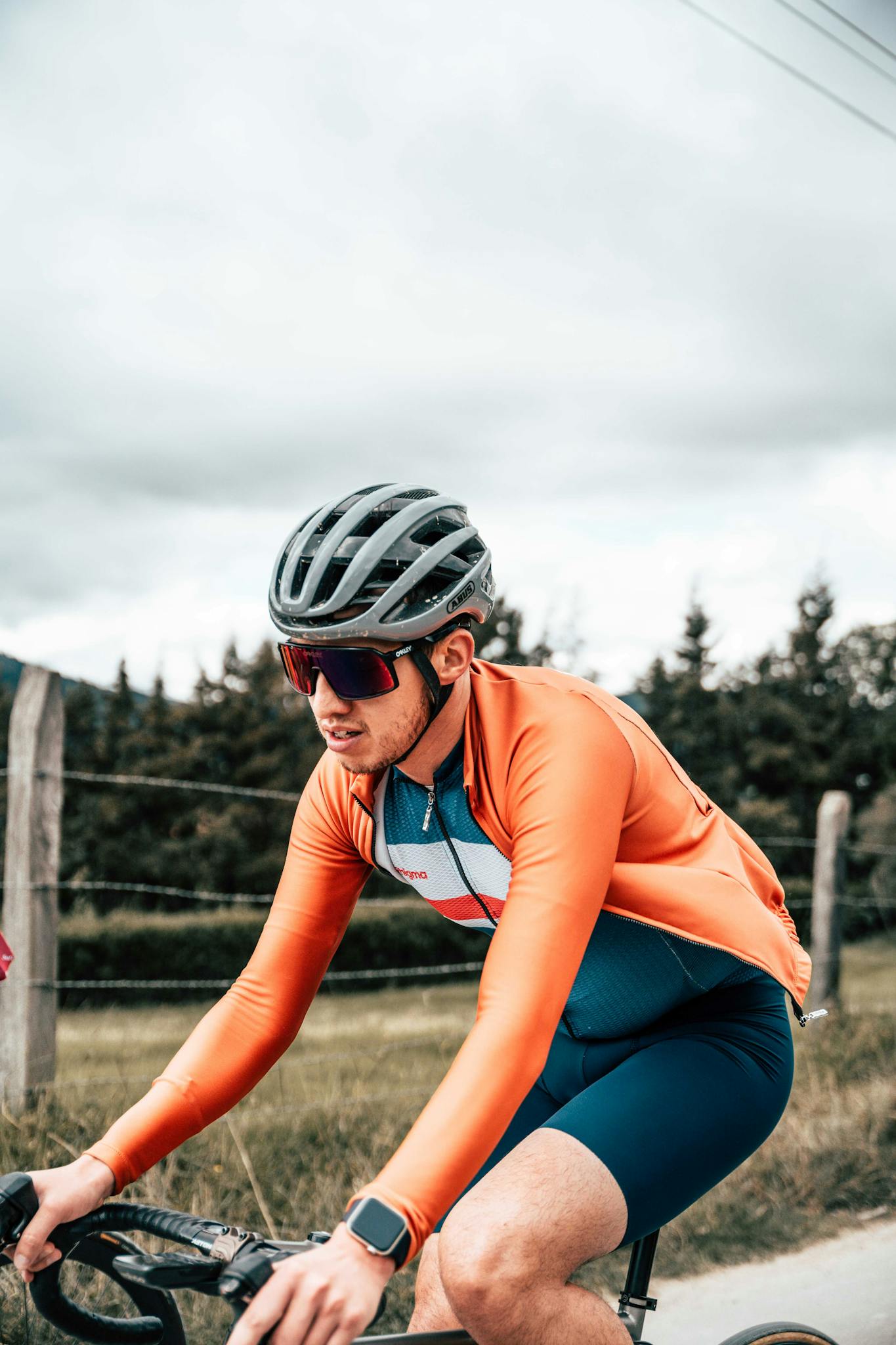 Man cycling outdoors wearing sportswear and helmet, focused on fitness training on rural road.
